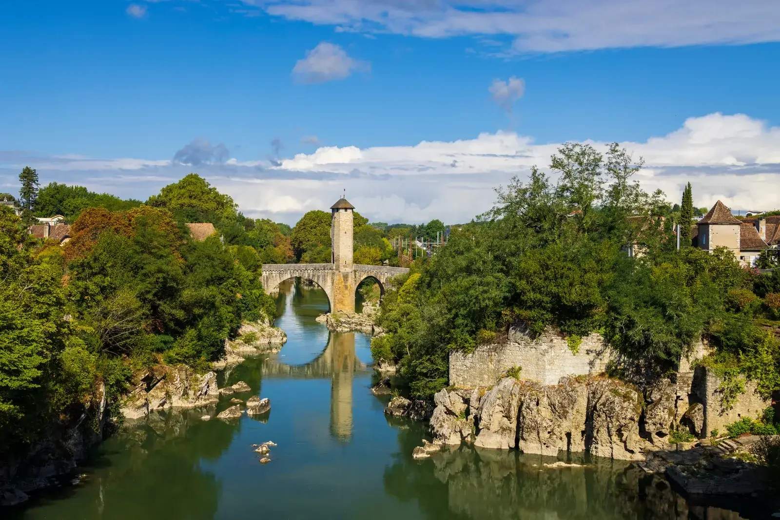 Le Pont Vieux d’Orthez et sa tour fortifiée franchissant le gave vert entre deux rives boisées