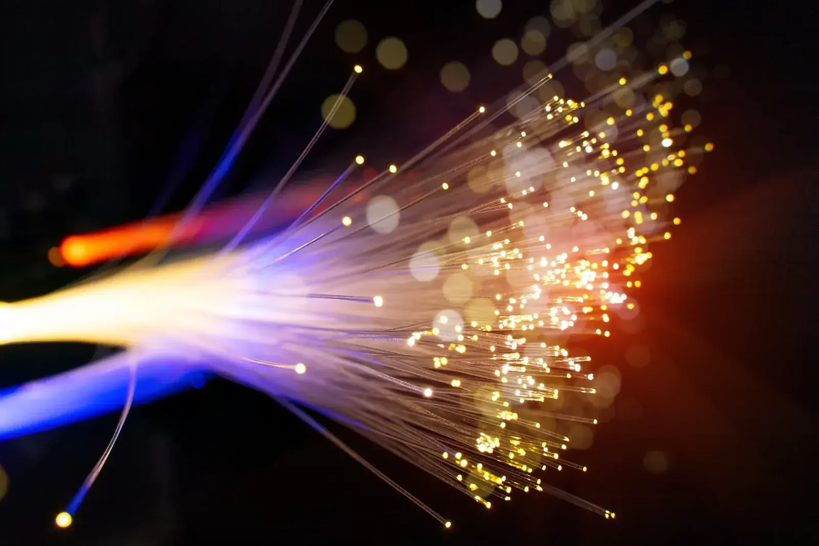 Extrémités lumineuses d’un faisceau de fibres optiques, points ambrés et filets bleus sur fond noir