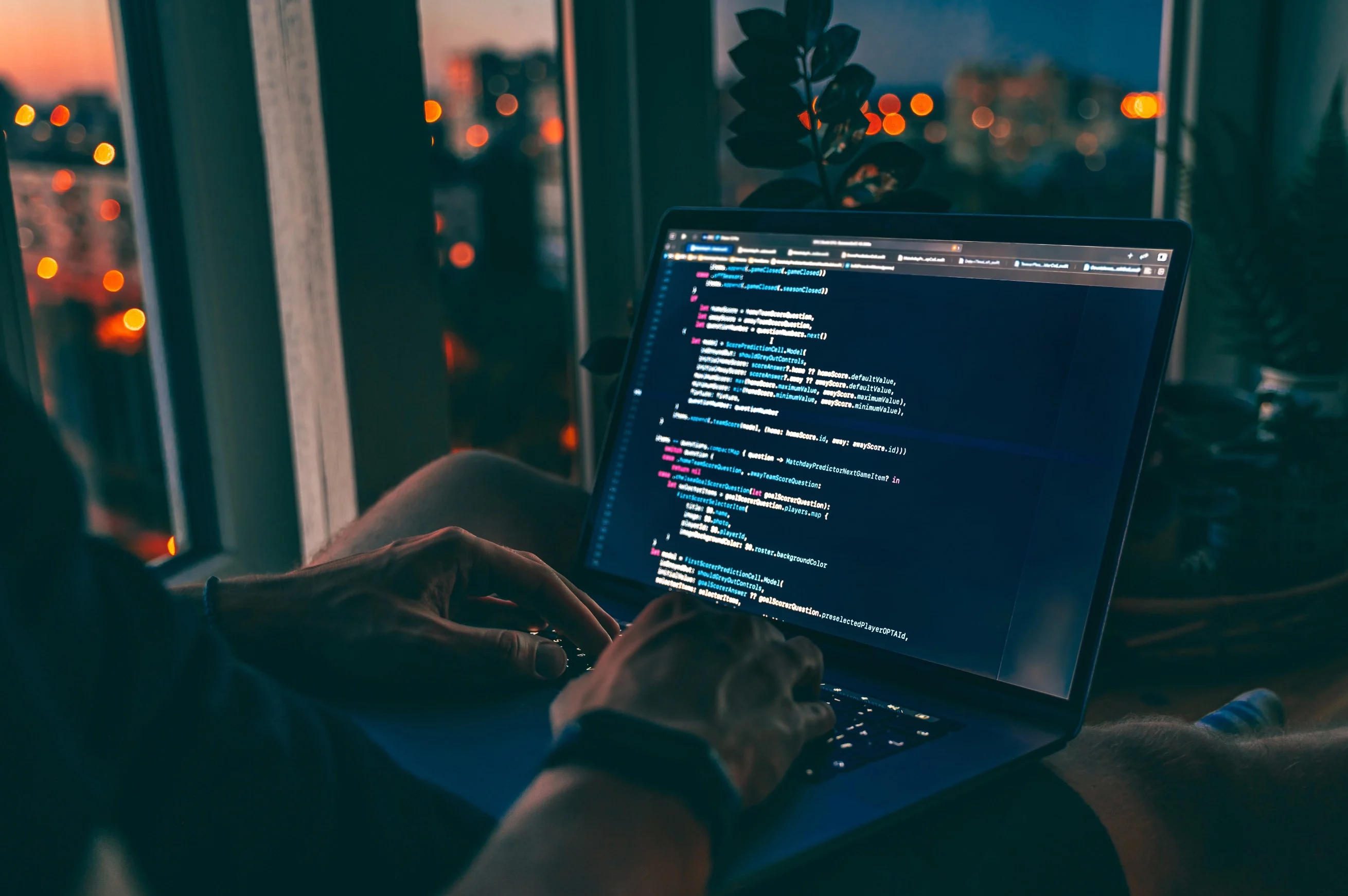 Personne travaillant le soir sur un ordinateur portable affichant du code