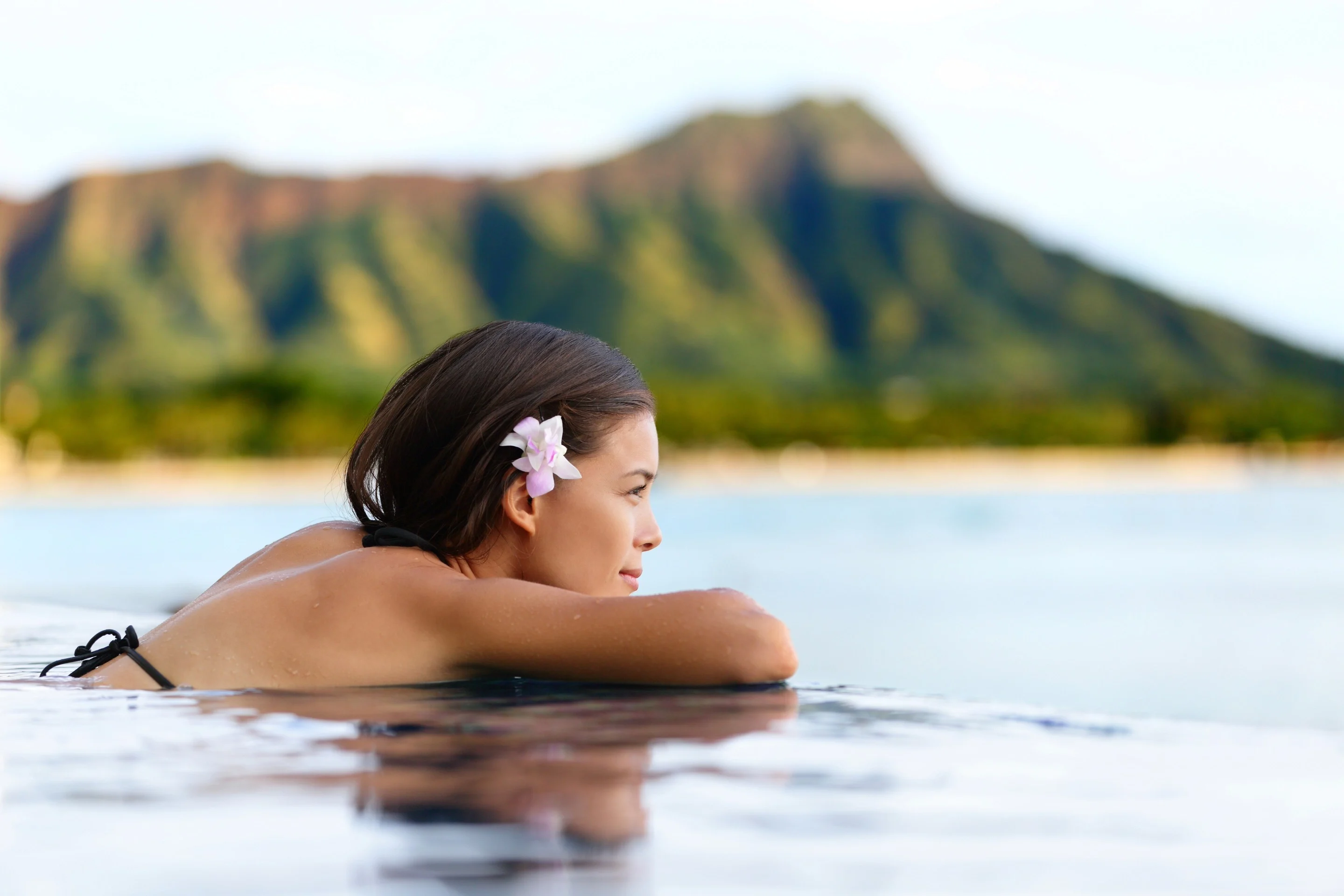 Femme se détendant dans l’eau face au cratère du Diamond Head, à Hawaï